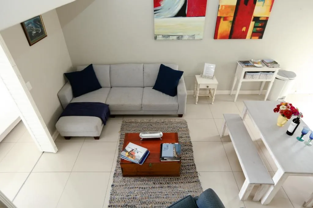Bright lounge with gray sofa, navy pillows, wooden coffee table, and colorful wall art