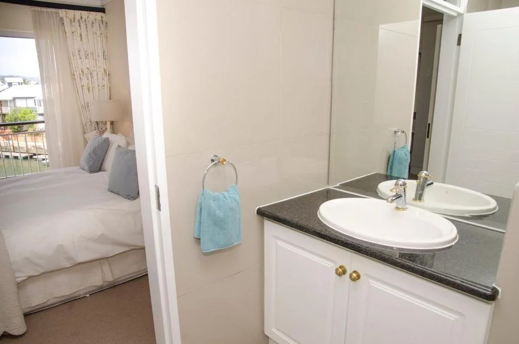 Ensuite bathroom with double vanity and black countertop adjacent to bedroom