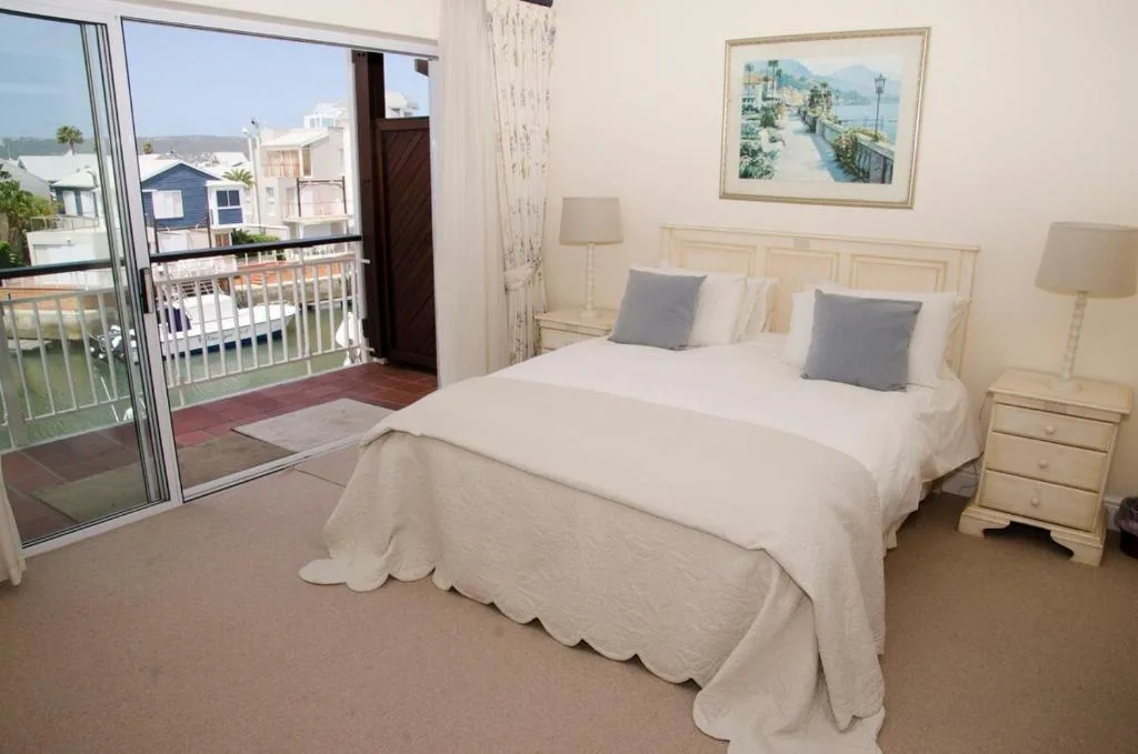 Bright bedroom with queen bed, balcony doors overlooking waterfront lagoon view