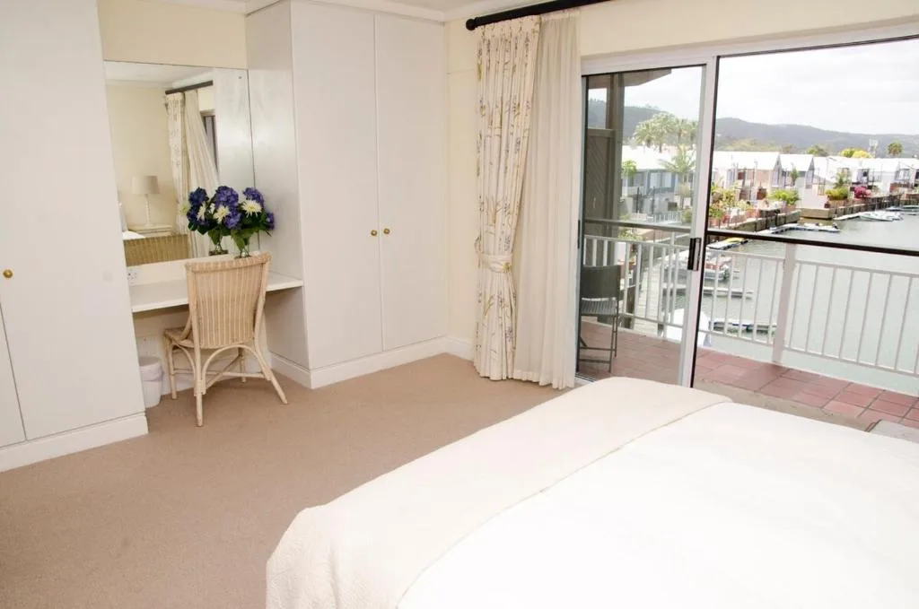 Spacious bedroom with waterfront and lagoon views through sliding glass doors