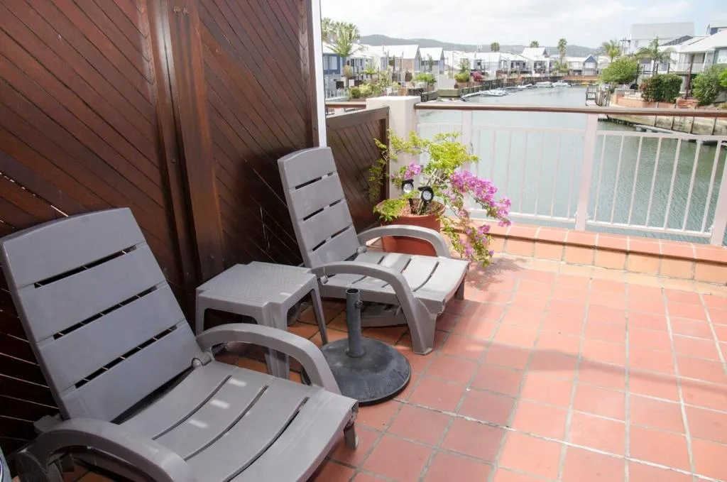 Terracotta patio with lounge chairs and flowering plants overlooking lagoon