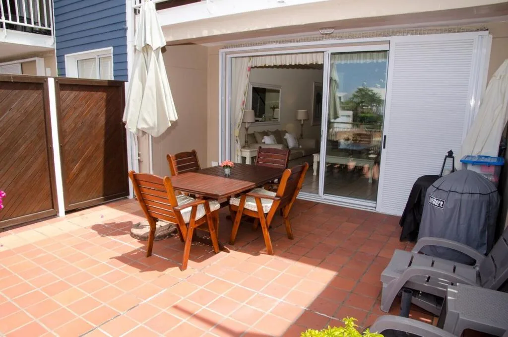 Outdoor patio with wooden dining table and chairs overlooking lagoon
