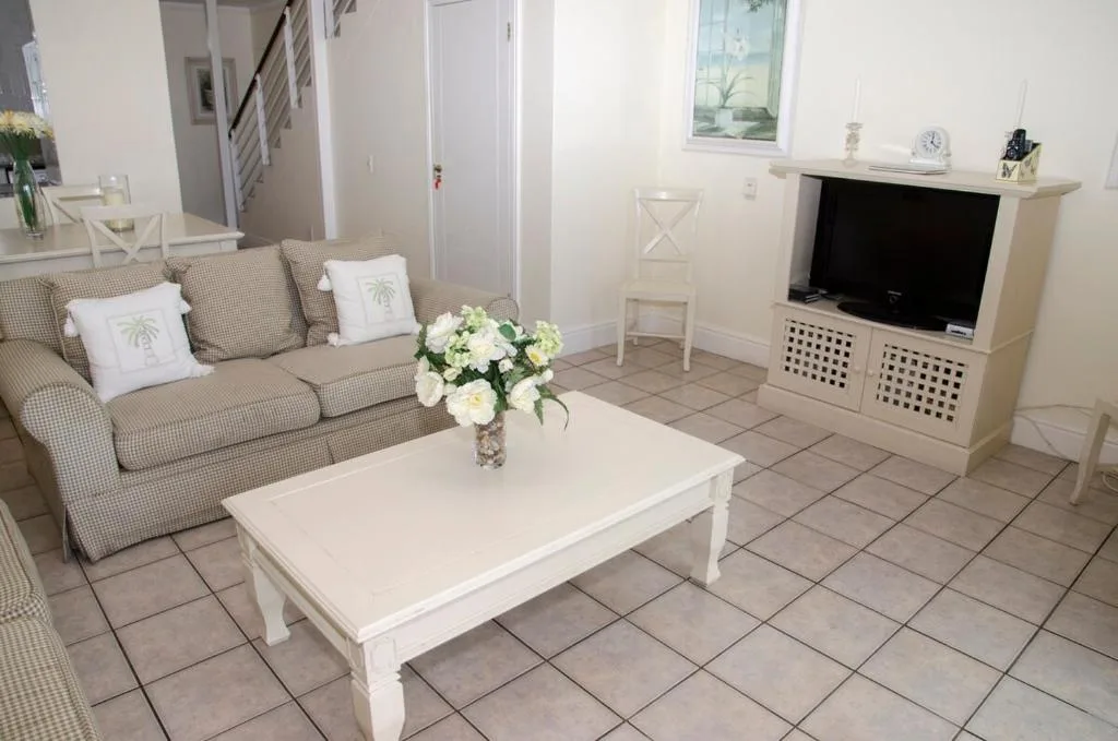 Bright living room with beige sofa, white coffee table, and television entertainment unit