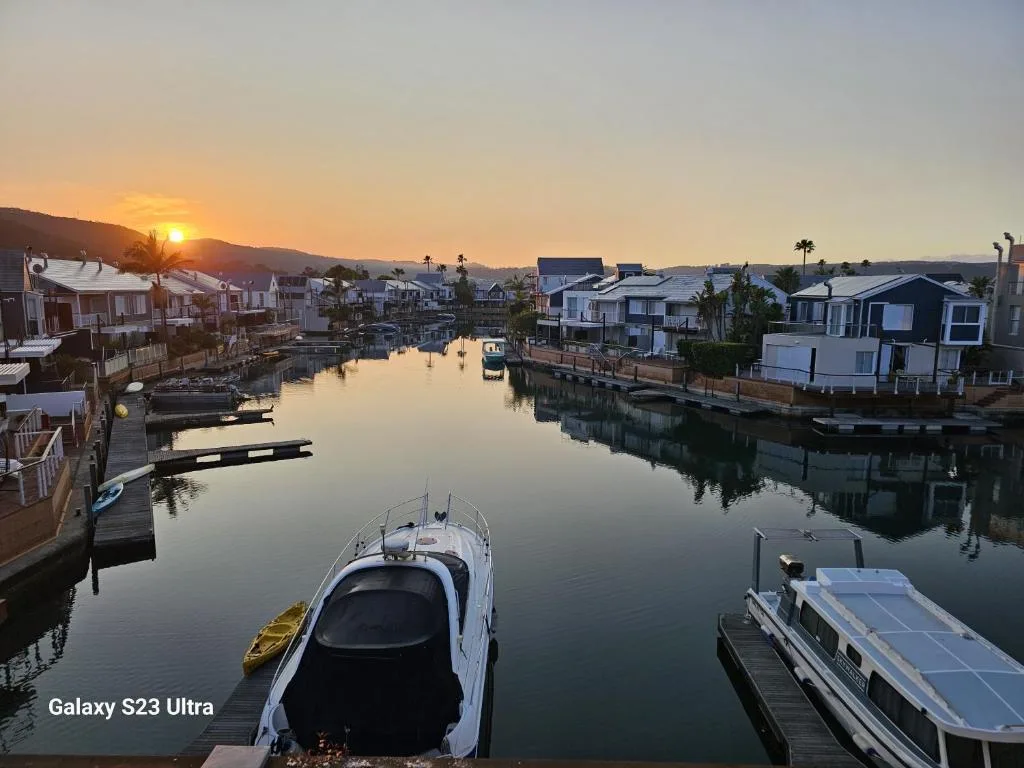 Sunrise over tranquil lagoon with moored boats and waterfront homes