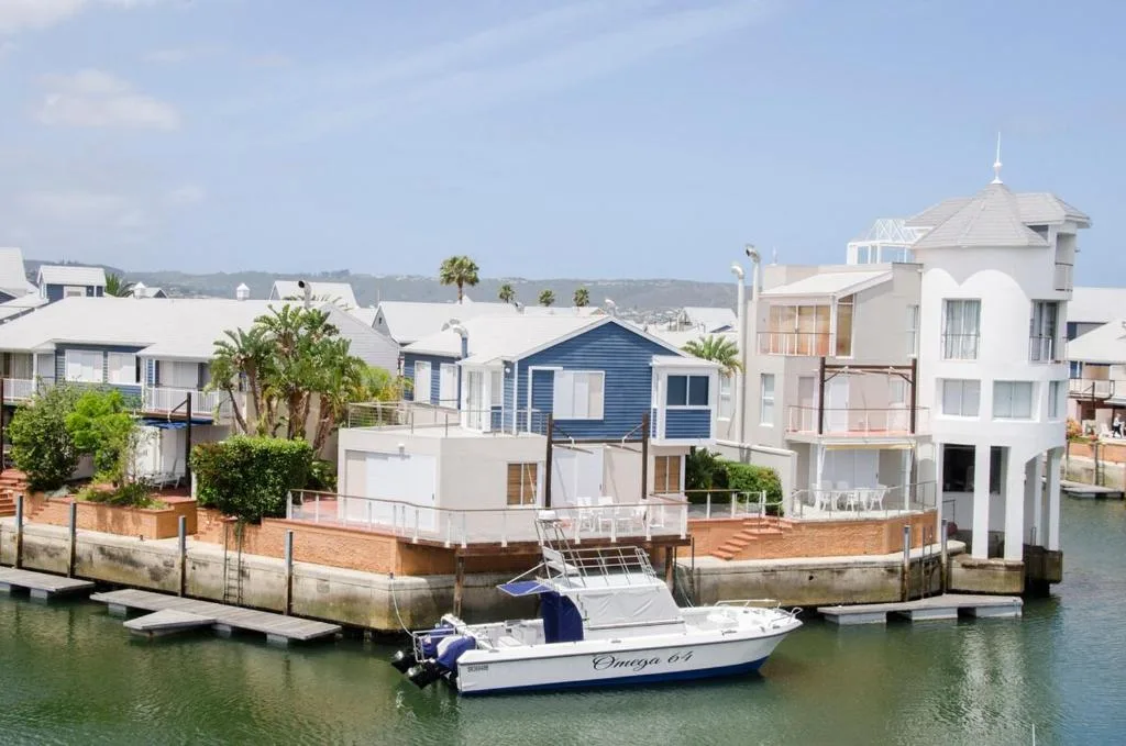 Waterfront homes and boats on Knysna Lagoon with mountain backdrop