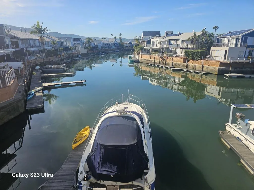 Serene lagoon waterfront with moored boats and surrounding residential properties