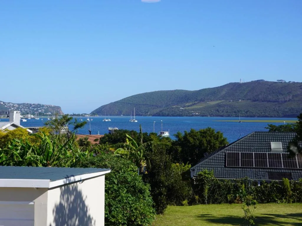 Stunning blue lagoon vista with forested hills and moored sailboats beyond