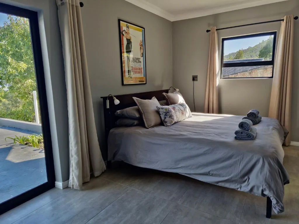 Bright bedroom with queen bed, rolled towels, and mountain views through windows
