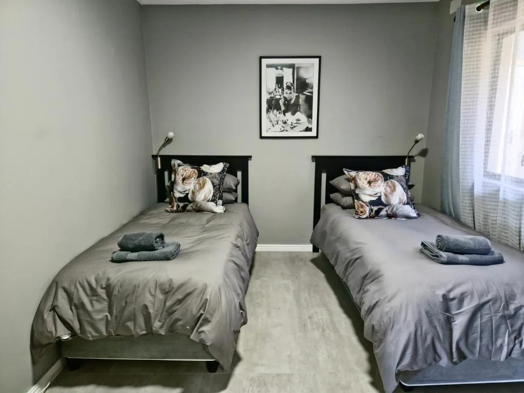 Twin bedroom with black frames, grey bedding, and framed artwork above beds