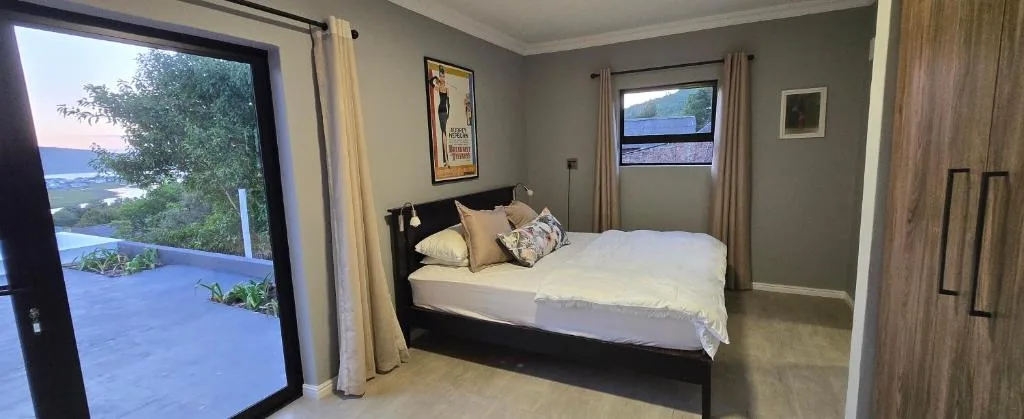 Modern bedroom with queen bed, ocean and lagoon views through large windows
