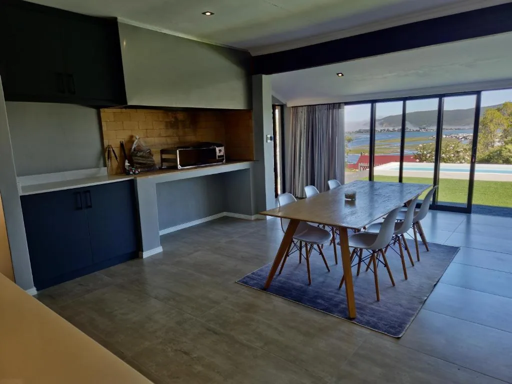 Modern dining table with chairs overlooking lagoon and garden views