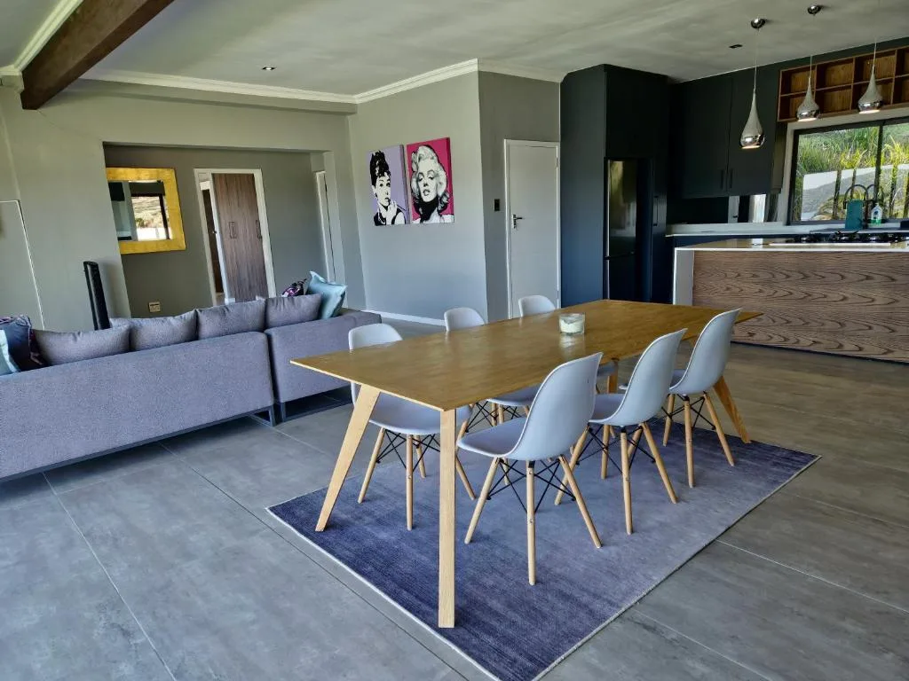 Modern dining table with white chairs and wood legs, open-plan interior
