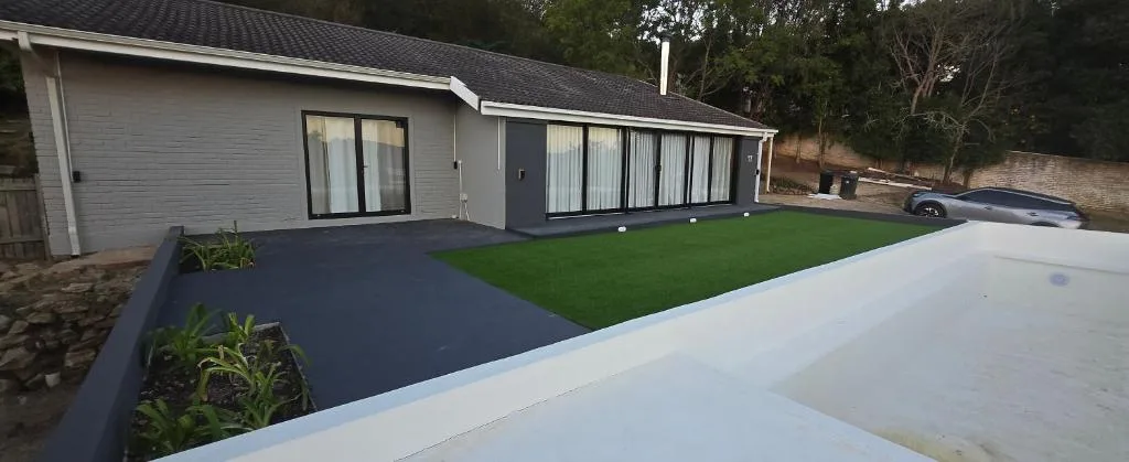 Modern holiday home with white facade, dark trim, and manicured lawn garden