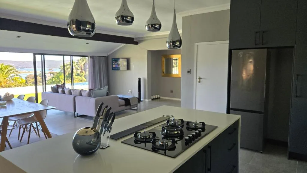 Modern kitchen with gas cooktop, island counter, pendant lights, and ocean views