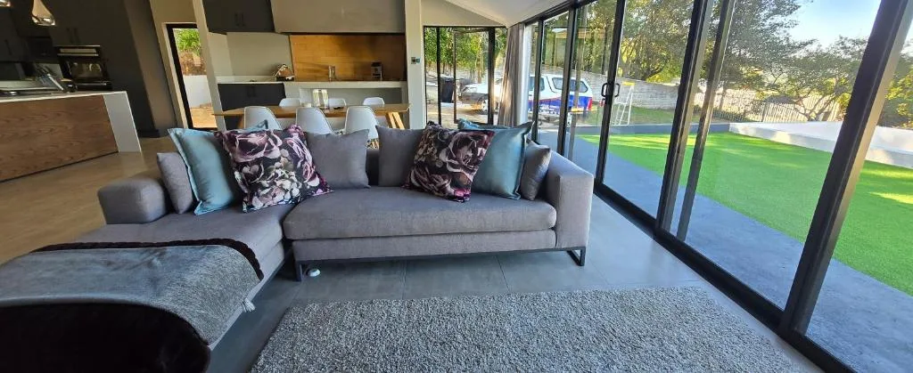 Modern lounge with gray sofa, patterned cushions, overlooking manicured garden