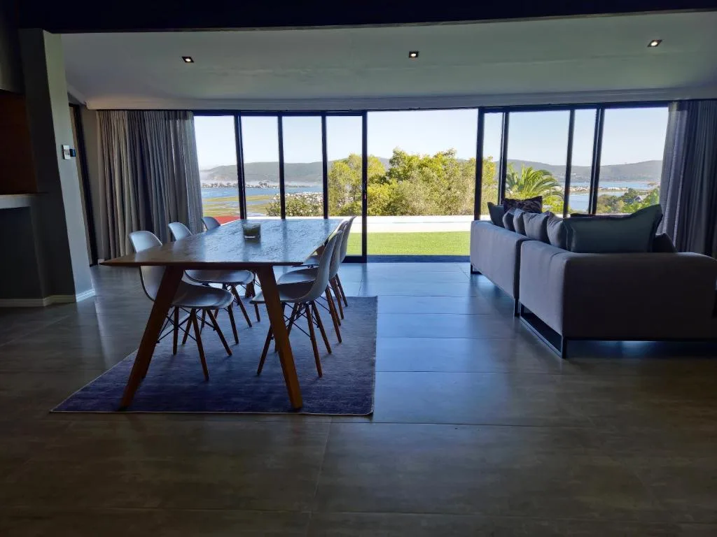 Modern lounge with sofa overlooking lagoon and mountains through glass doors