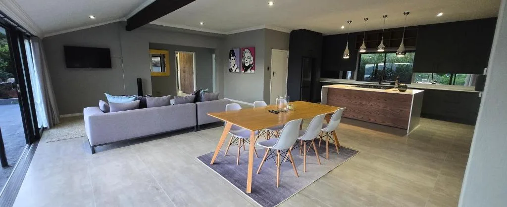 Open-plan living area with gray sofa, dining table, and modern kitchen