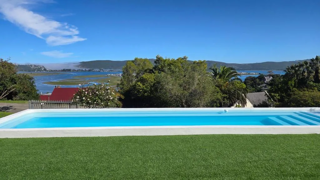 Modern rectangular swimming pool with lagoon and mountain views beyond
