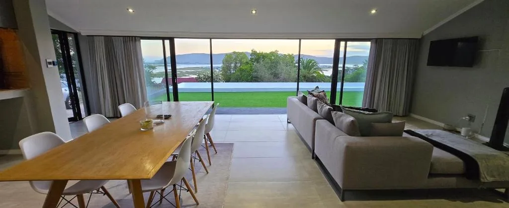 Lagoon and mountain views through expansive windows overlooking green lawns