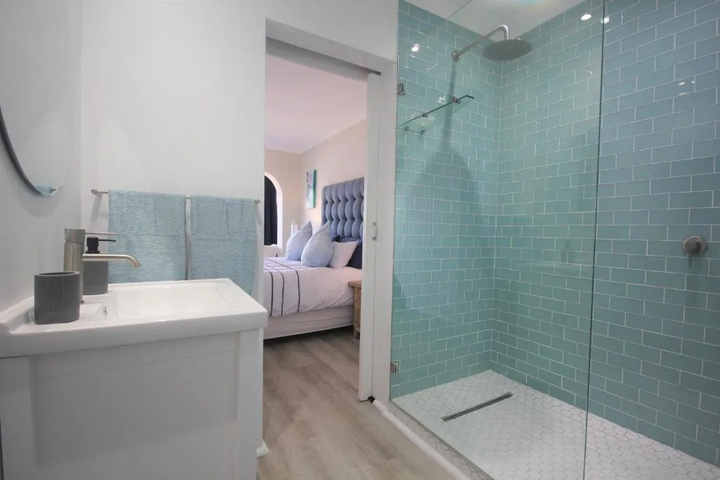 Modern turquoise tiled bathroom with rainfall shower and white vanity