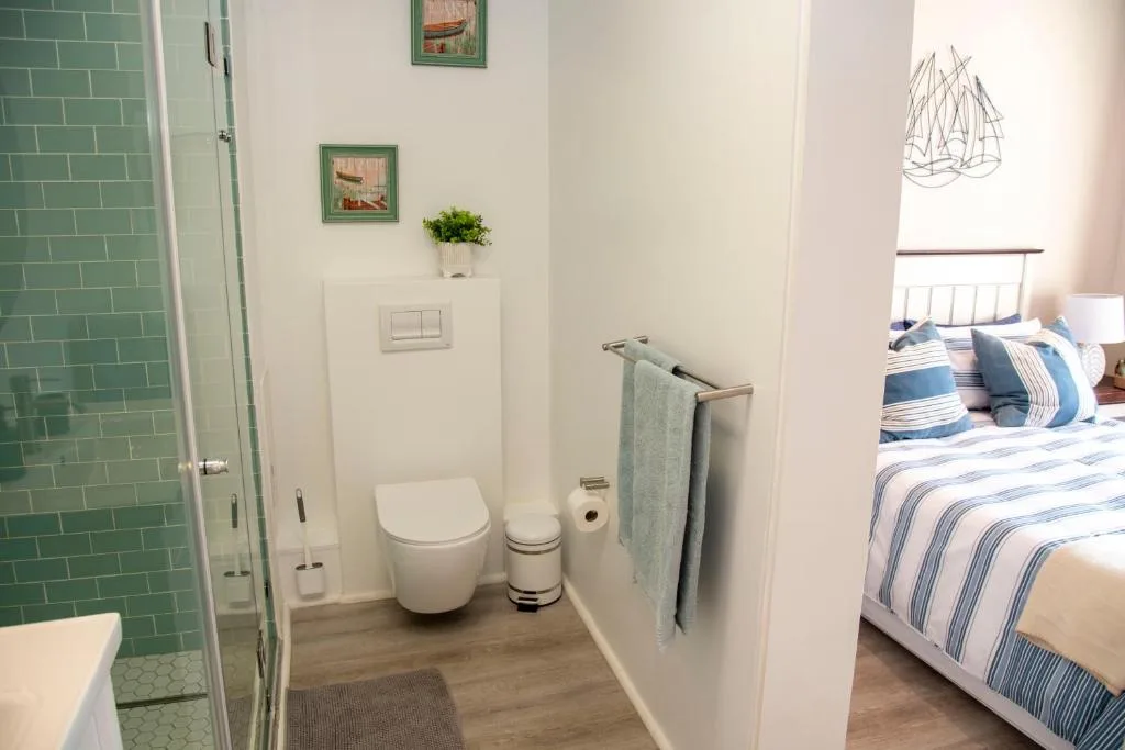 Modern bathroom with green subway tile shower, wall-mounted toilet, and coastal decor