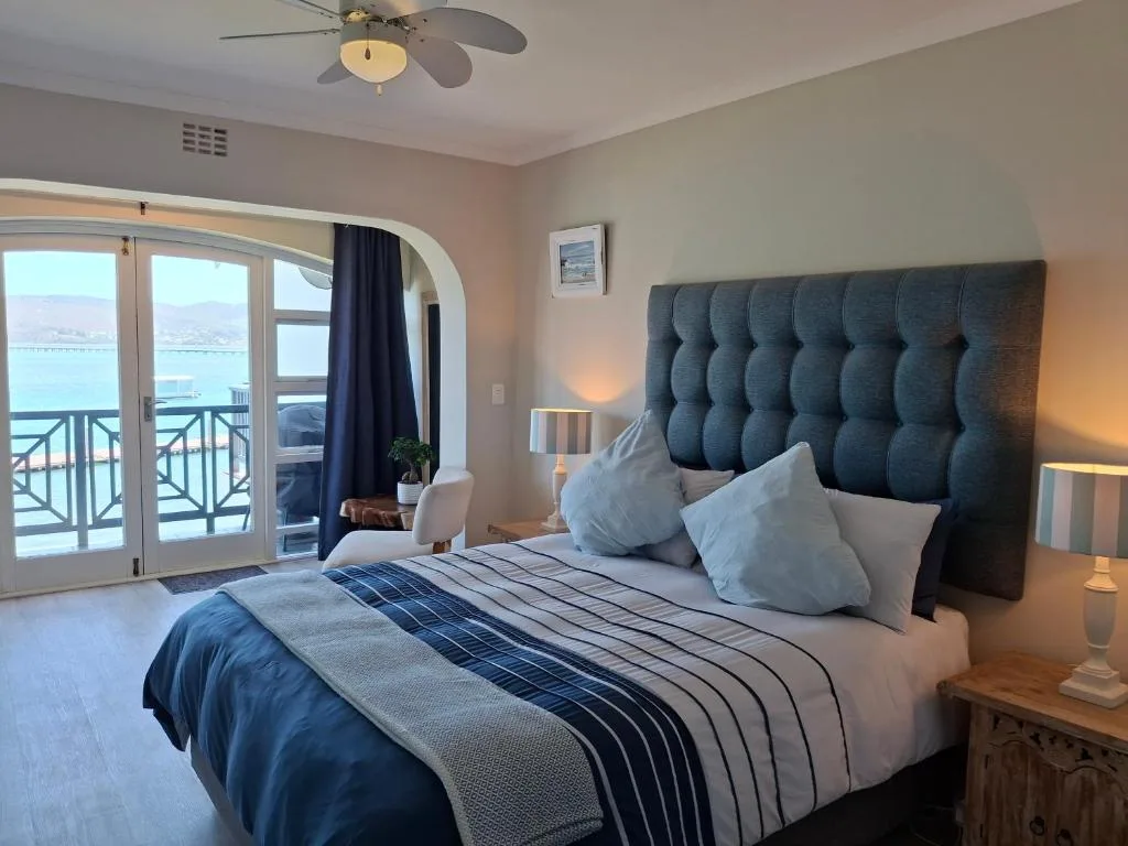 Spacious bedroom with ocean view through glass doors and balcony access