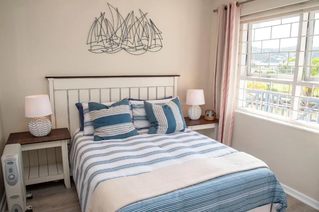 Bright bedroom with striped bedding, metal headboard, and scenic window views
