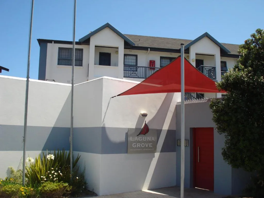 Modern white apartment building with red accents and shaded patio area
