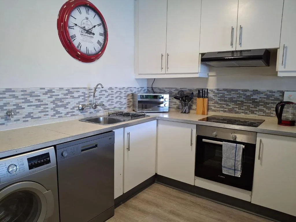 Modern kitchen with white cabinetry, stainless steel appliances, and mosaic backsplash