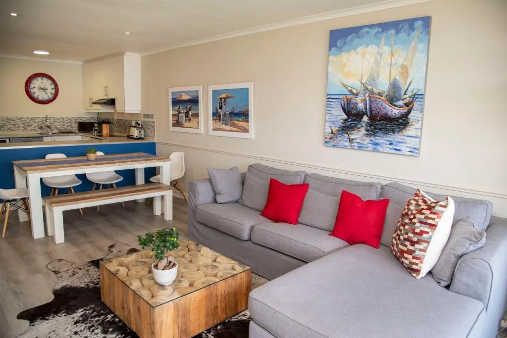 Modern lounge with gray sectional sofa and red cushions overlooking kitchen area