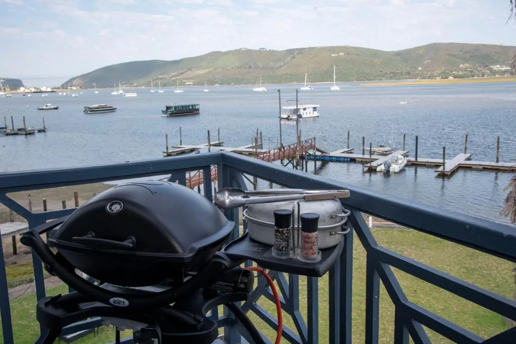 Scenic lagoon view with boats, mountains, and braai area overlooking Knysna Heads