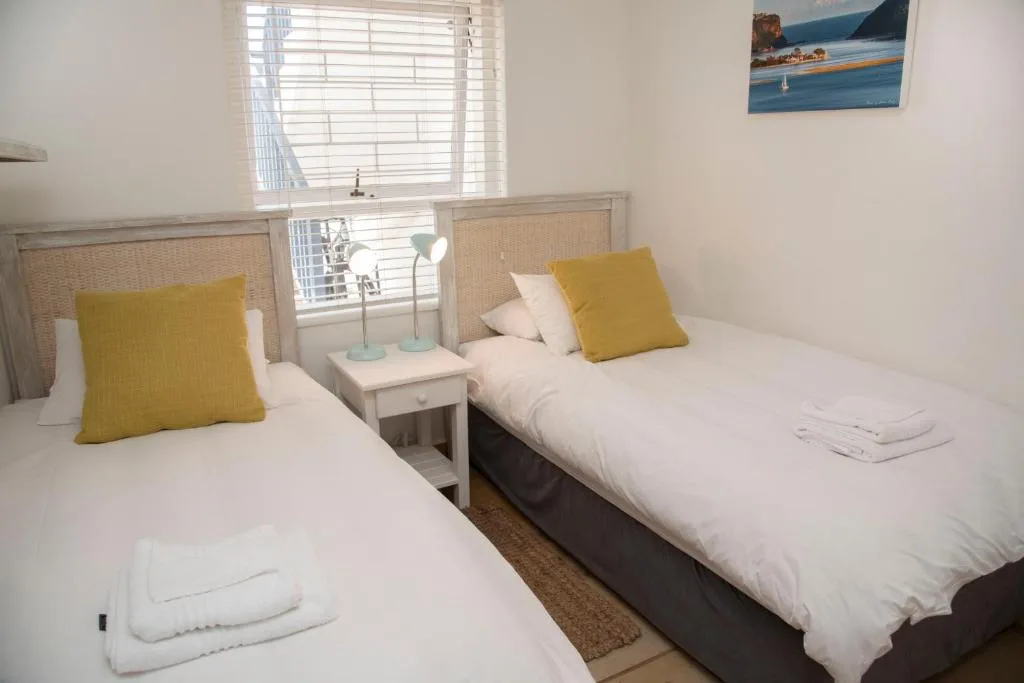 Twin bedroom with yellow pillows, white bedding, and natural light from window