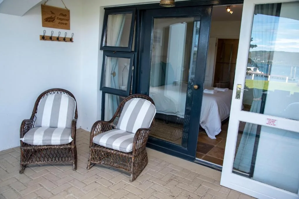 Wicker chairs with striped cushions on tiled patio overlooking water