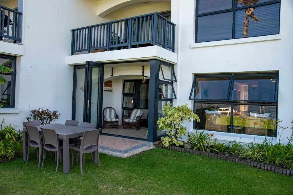 Outdoor patio with dining table, chairs, and manicured garden area