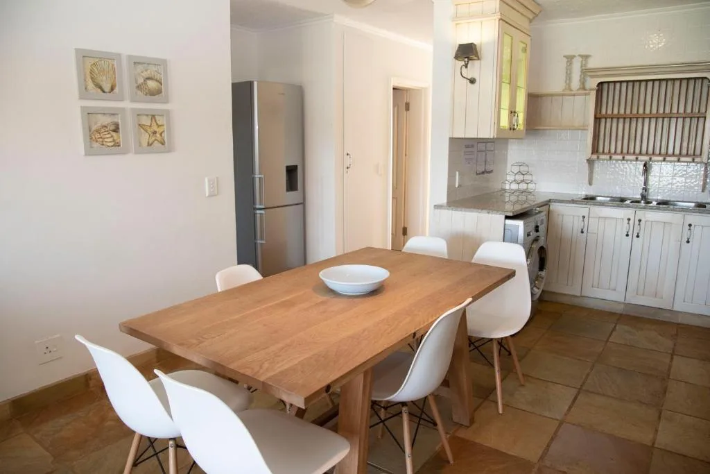 Wooden dining table with white chairs in open-plan kitchen area