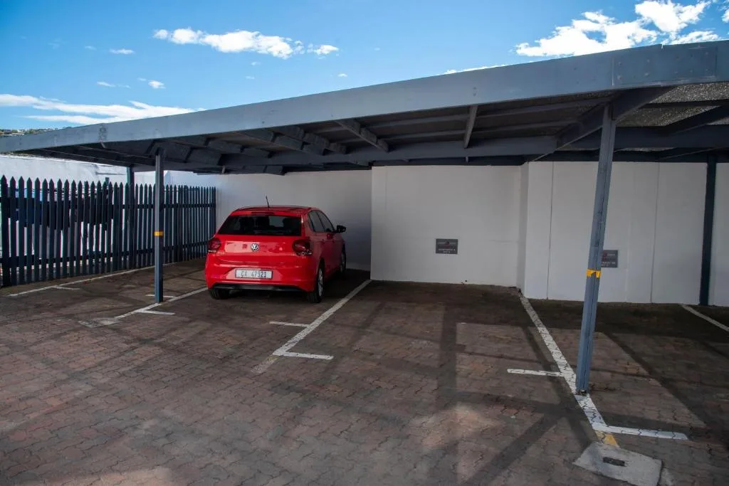 Covered carport with red vehicle parked underneath metal structure