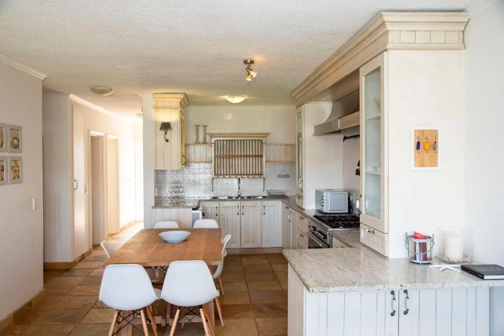 Open-plan kitchen and dining area with white cabinetry and granite counters