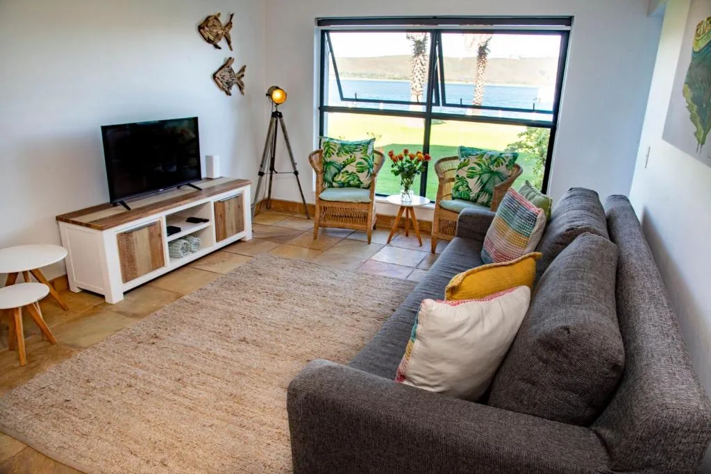 Spacious lounge with grey sofa, TV, ocean view through large windows
