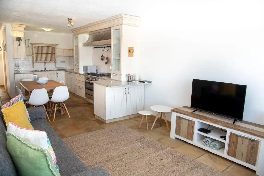 Open-plan lounge and kitchen with sofa, TV, and dining area