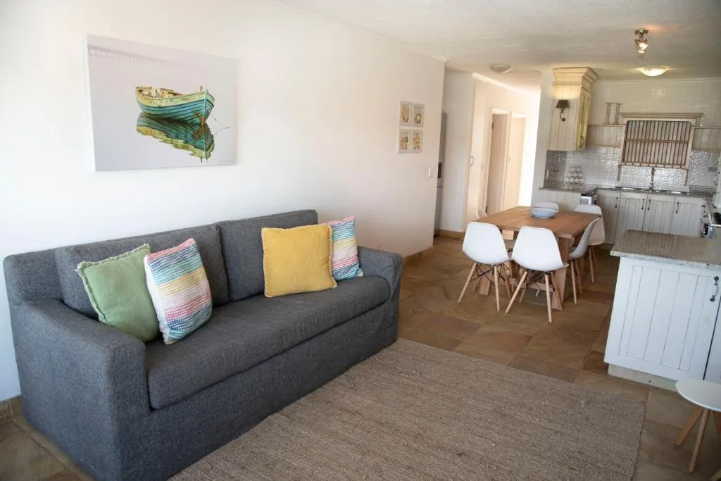 Spacious open-plan lounge with gray sofa, colorful cushions, dining area visible beyond