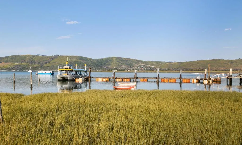 Scenic lagoon view with moored boats and green hillsides beyond