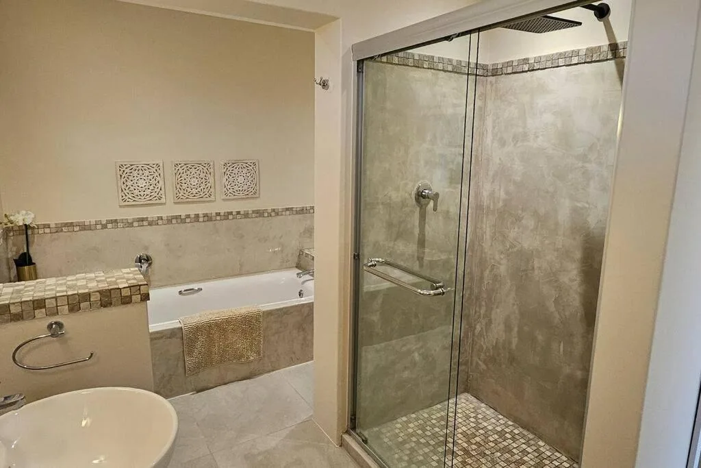 Modern bathroom with walk-in shower enclosure, bathtub, and round sink