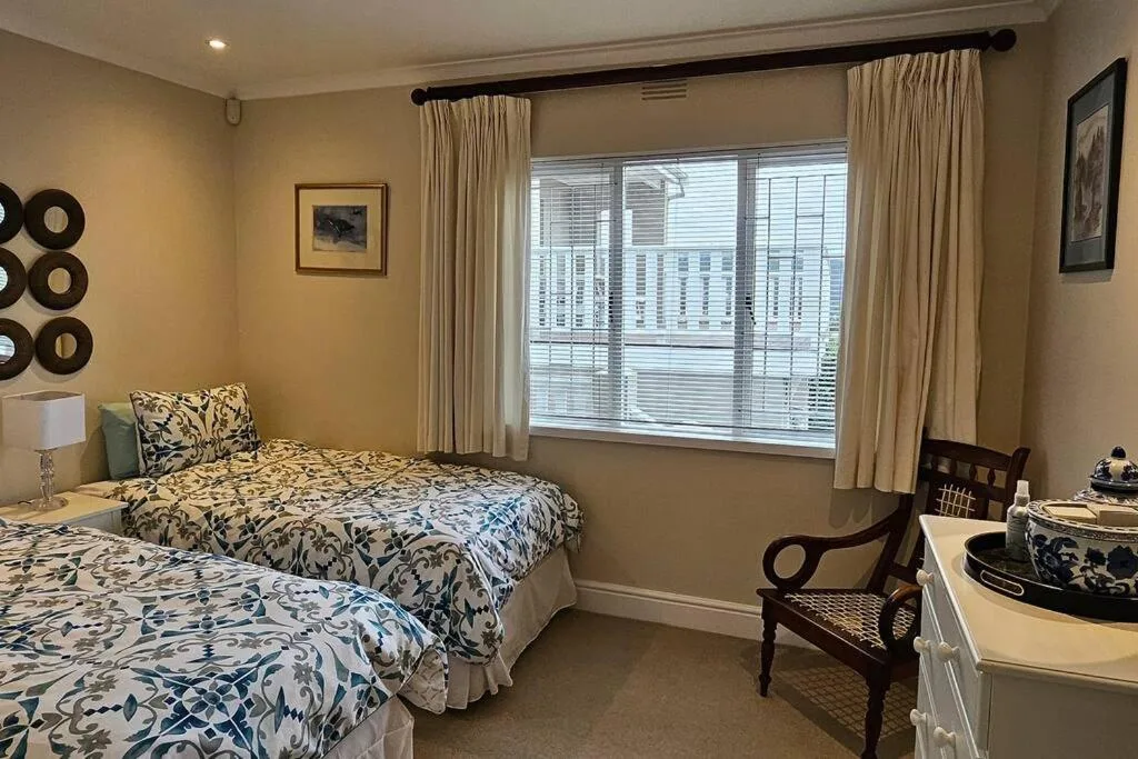 Twin bedroom with patterned bedding, elegant curtains, and garden views