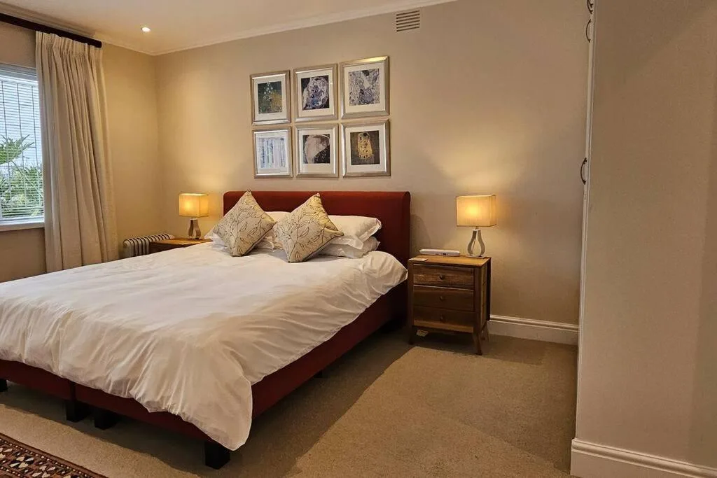 Spacious bedroom with burgundy bed, white linens, and warm ambient lighting
