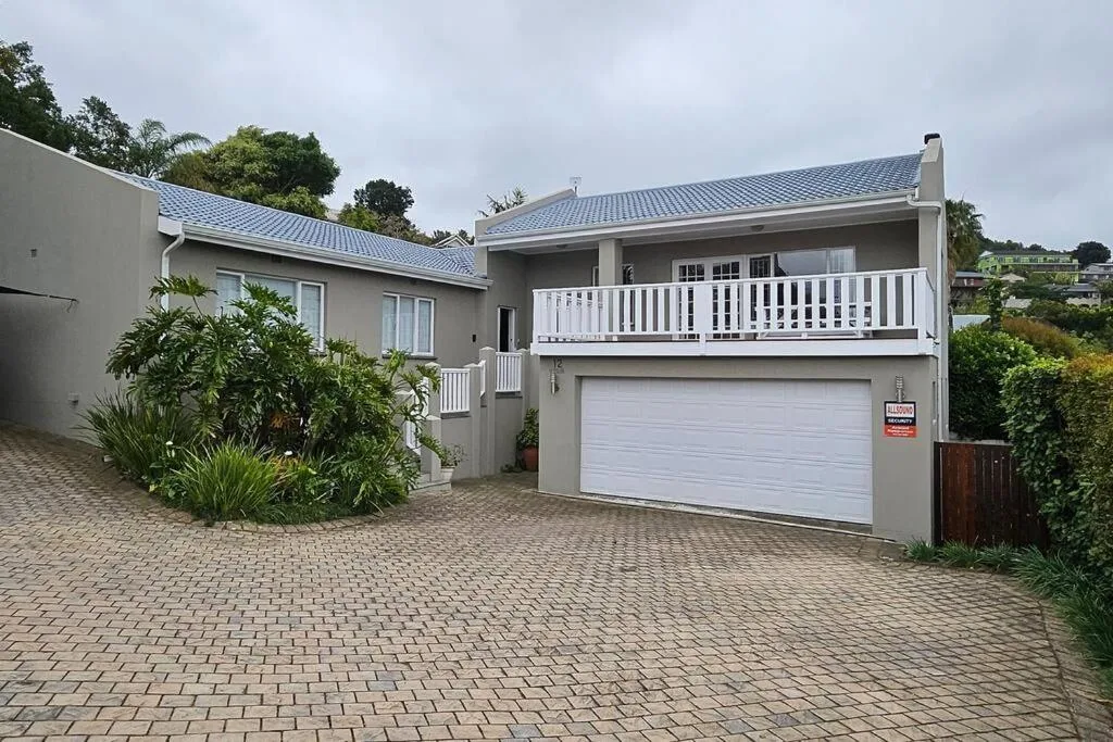Modern white house with blue roof and double garage on paved driveway