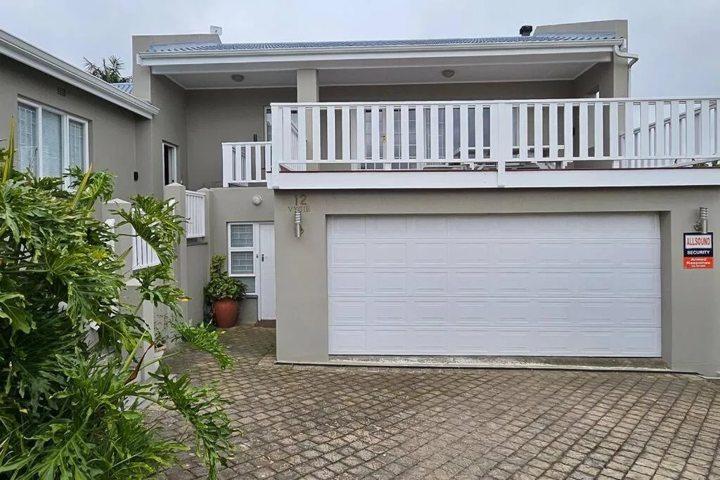 Modern gray house with white deck railings and garage driveway