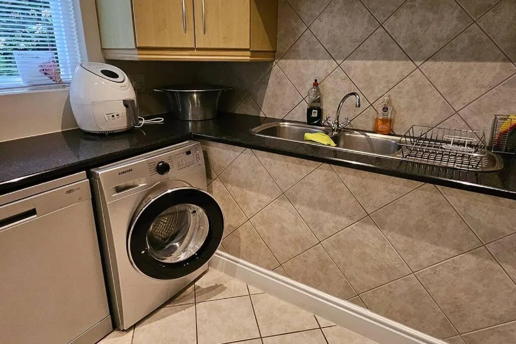 Modern kitchen with washing machine, sink, stove, and black countertops