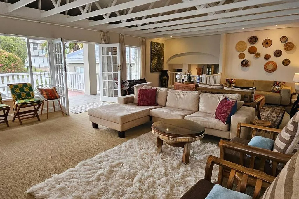 Spacious living room with beige sectional sofa, round coffee table, and deck access