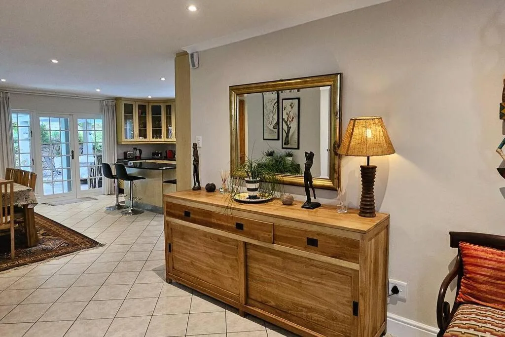 Modern lounge with wooden dresser, decorative mirror, and open-plan layout