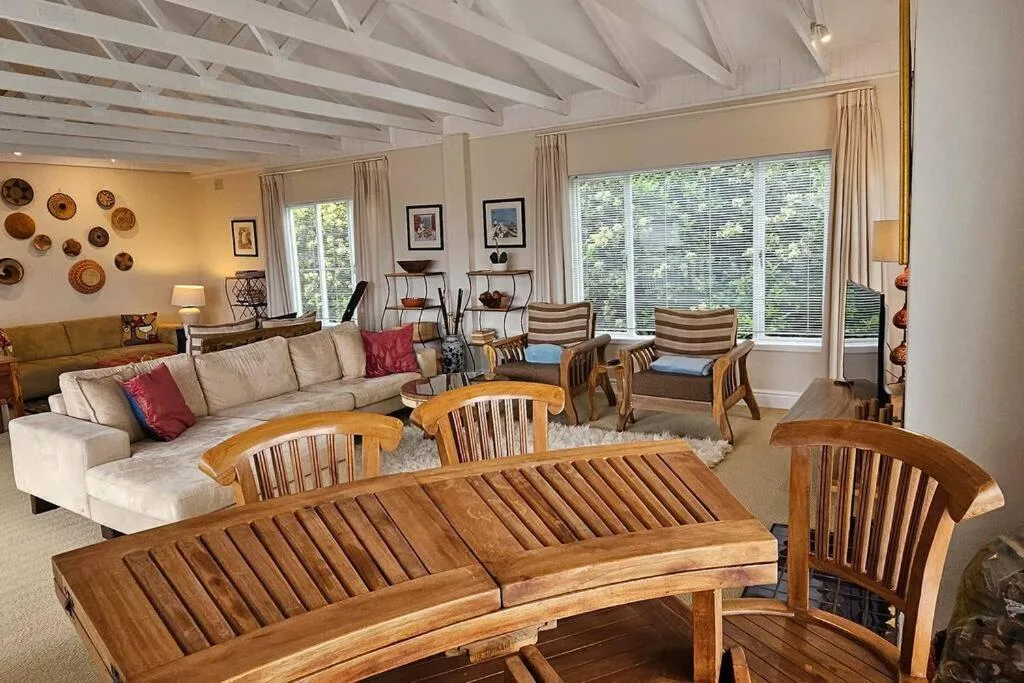 Spacious lounge with cream sectional sofa, wooden chairs, and exposed beam ceiling